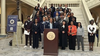 A group of black lawmakers and advocates stand on steps inside the State Capitol.