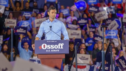 Jon Ossoff looks at the crowd at a rally while standing at a podium