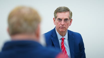 Brad Raffensperger looks at a man in a white room