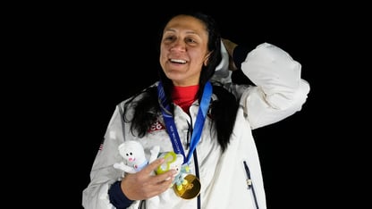 Elana Meyers Taylor wears a gold medal while holding a little plushie