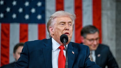 President donald trump stands behind a lectern at the state of the union address, with vice president j d vance and house speaker mike johnson behind him