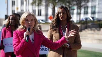 Jen Jordan holds a microphone and speaks while Miracle Rankin stands next to her