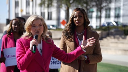 Jen Jordan holds a microphone and speaks while Miracle Rankin stands next to her