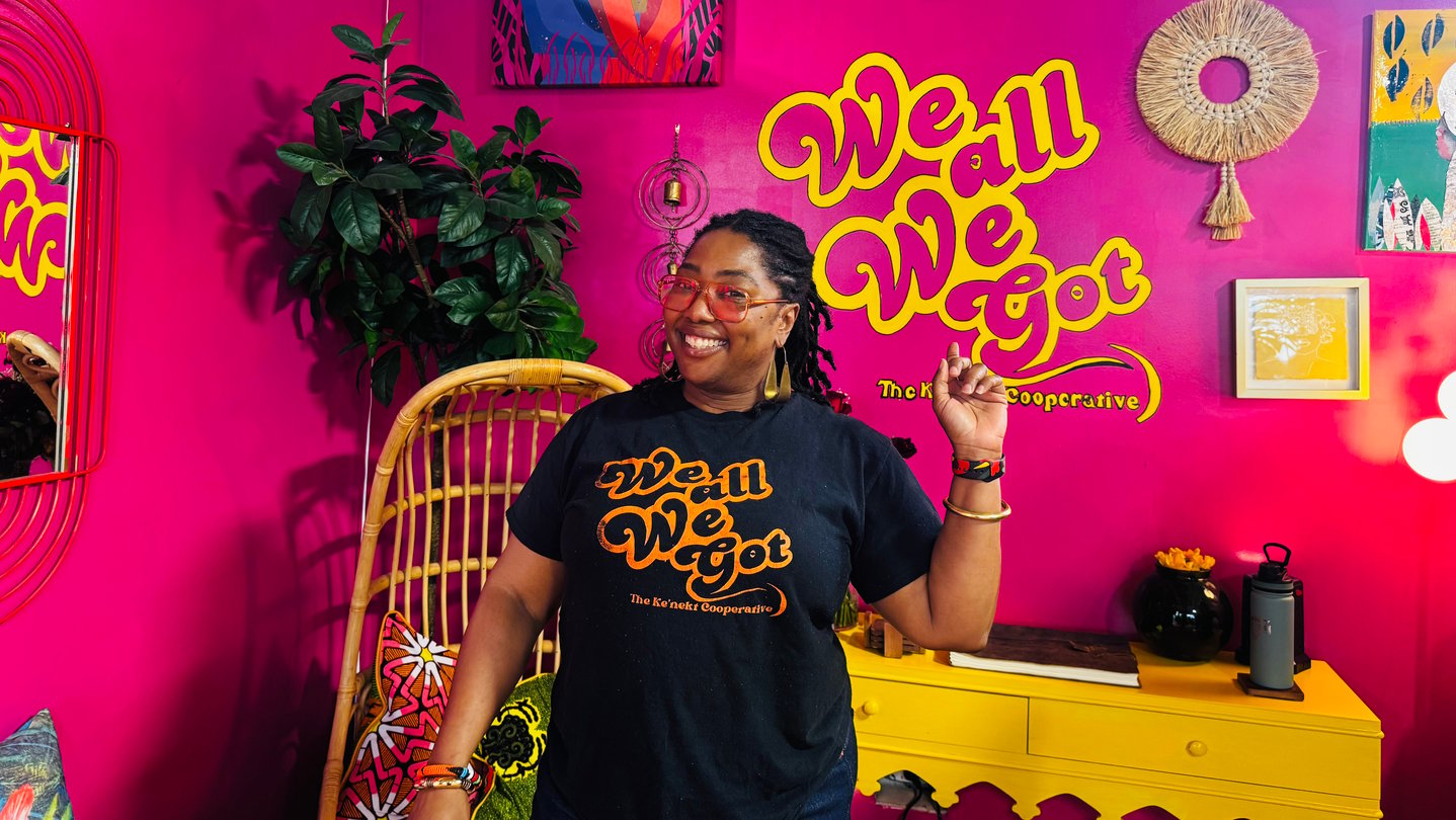 A woman stands in a pink room with a lot of decorations on the wall