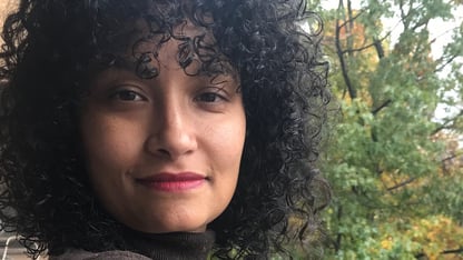 Director Jamila Wignot outdoors, wearing a brown top, with trees in the background.