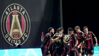 A team huddles near the Atlanta United sign