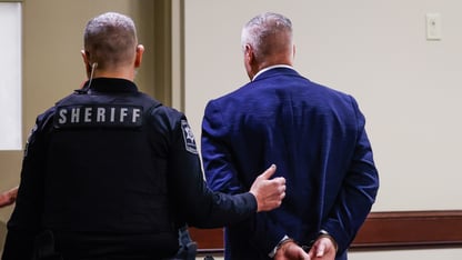 Colin Gray is handcuffed and escorted out of a room