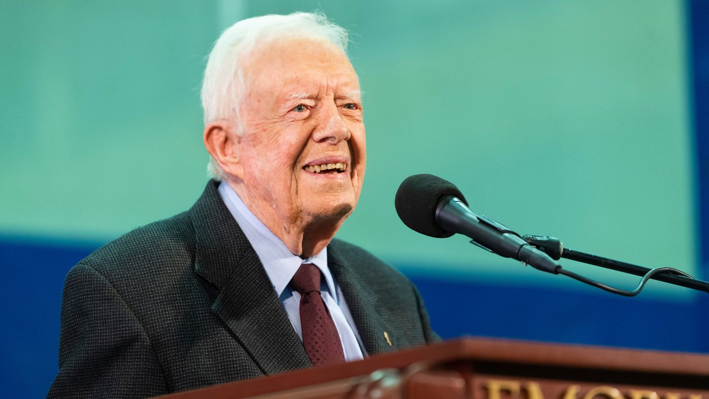 Former President Jimmy Carter stands behind a podium at an event