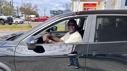 A man sitting in his car posing for a photo.