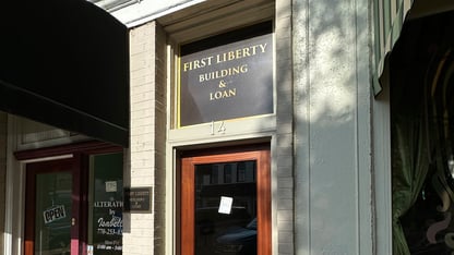 A dark sign above a wooden door for the First Liberty Building