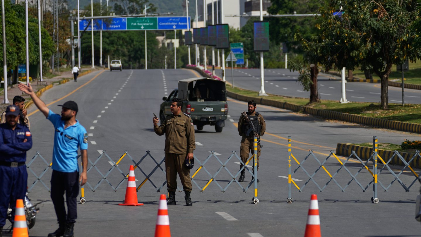 People stand at a barrier in the middle of the street