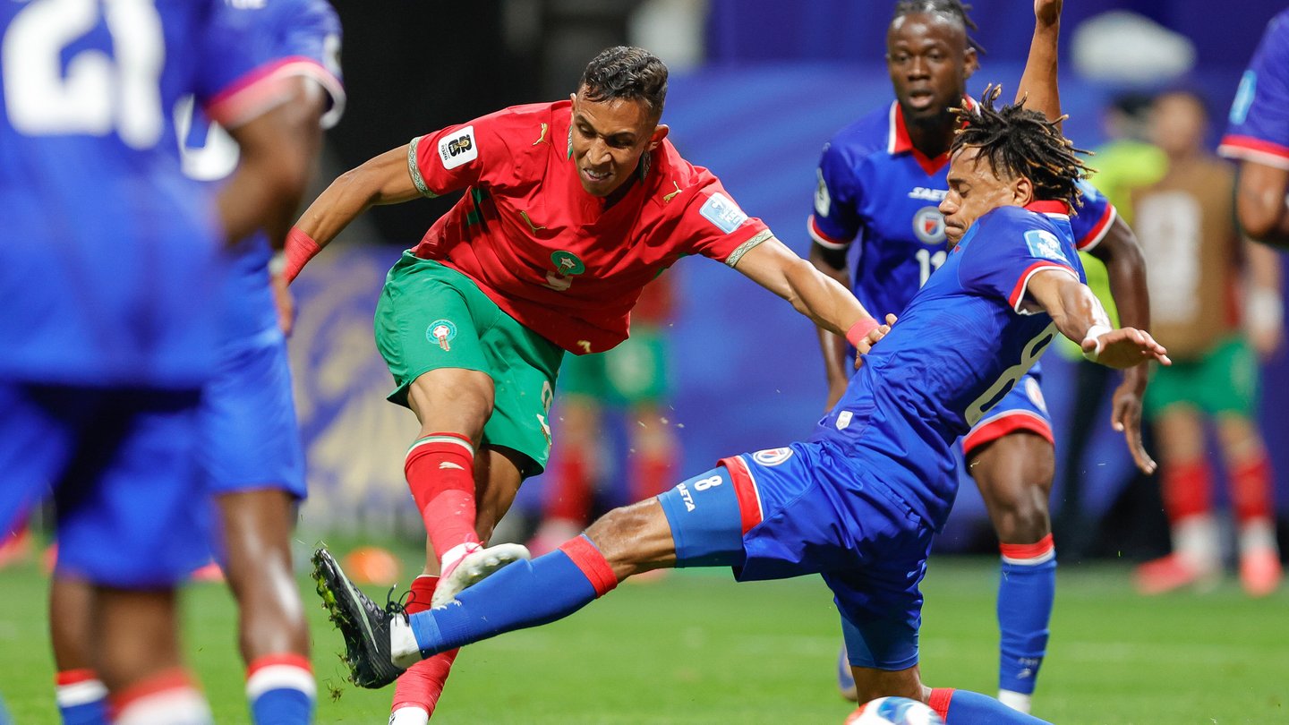 Two players fight for a soccer ball with the person on the right extending his leg