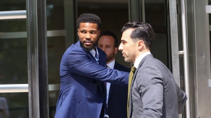 A man holds open a door while two other men walk through