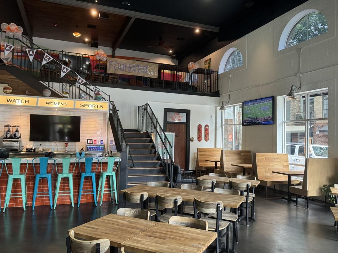 The inside of a restaurant's dining room is shown with a bar and several tables and chairs, along with a staircase going to a second-floor lounge