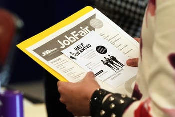 A person holds a folder and sheets of paper saying 