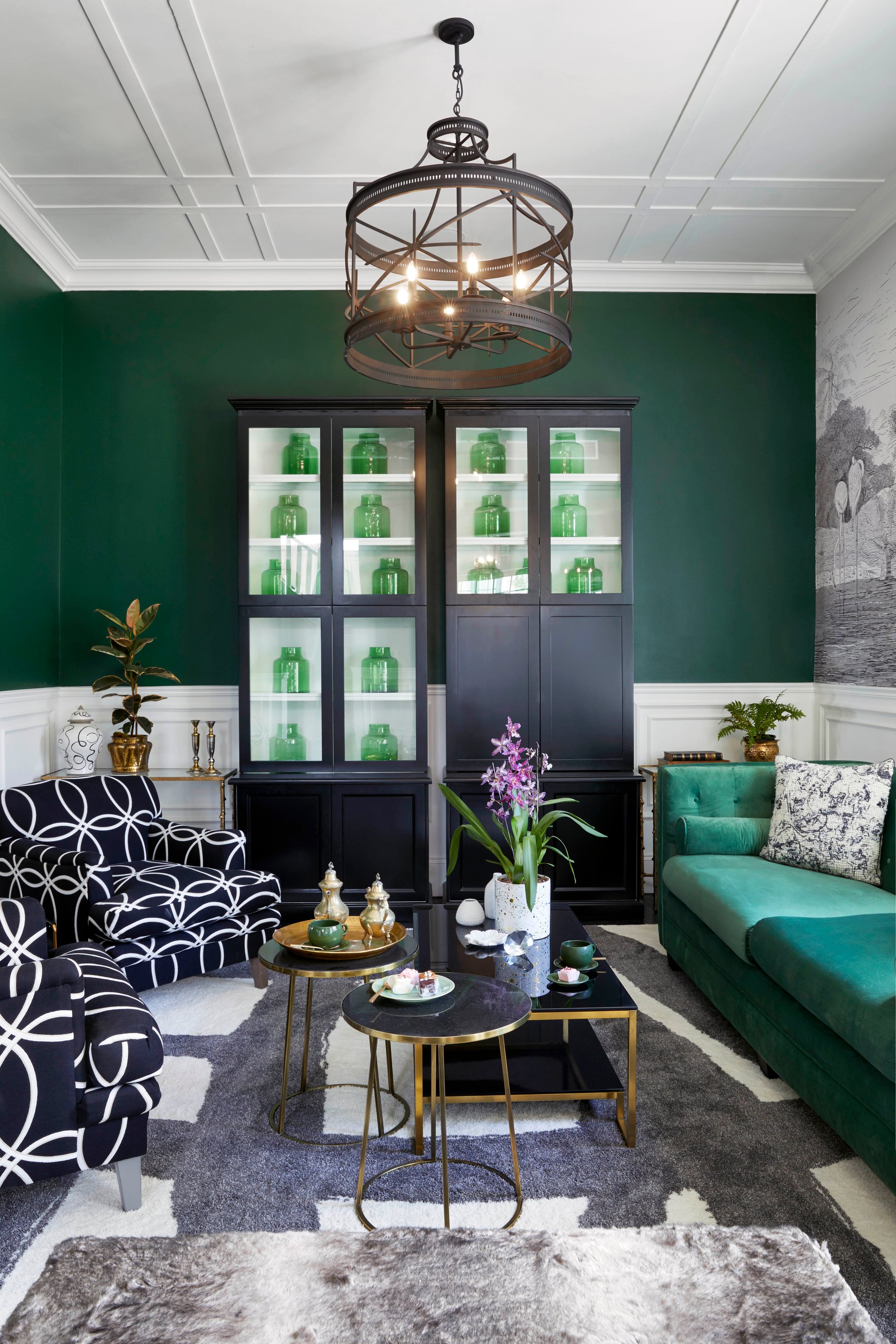 Emerald green lounge with velvet sofa, glass display cabinet, and brass accents at Cape Cadogan.