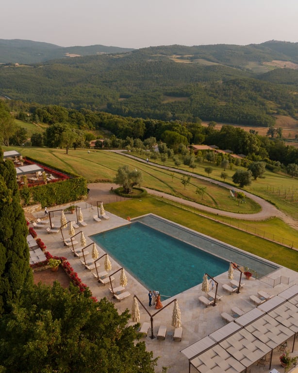 Luxury swimming pool at Castello di Casole surrounded by Tuscan countryside, offering serene views and elegant loungers perfect for relaxation.