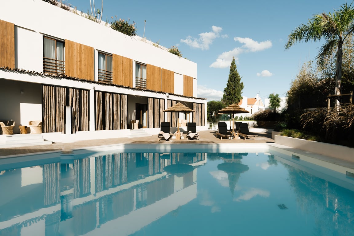 This Breezy Boutique Hotel Is the Perfect Addition to the Seaside Village of Comporta, Portugal | AlmaLusa Comporta exterior view | AlmaLusa Comporta lobby | AlmaLusa Comporta bedroom | AlmaLusa Comporta indoor seating | AlmaLusa Comporta outdoor seating | AlmaLusa Comporta outdoor pool