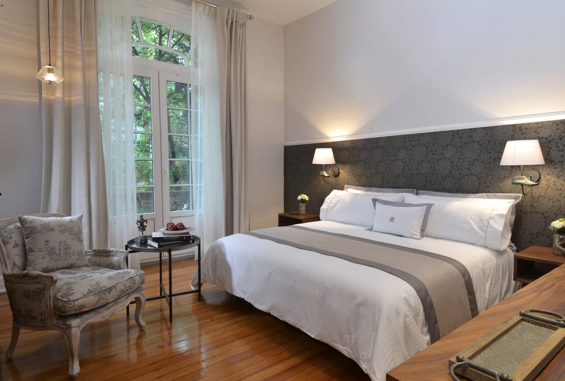 This Boutique Hotel in a Charming Pink Building Is Mexico City's Hidden Gem | Casa Goliana in Mexico City suite bathroom | Casa Goliana in Mexico City king suite | Casa Goliana in Mexico City outdoor breakfast | Casa Goliana in Mexico City bedroom suite | Casa Goliana in Mexico City outdoor patio | Casa Goliana in Mexico City suite seating | Casa Goliana in Mexico City exterior