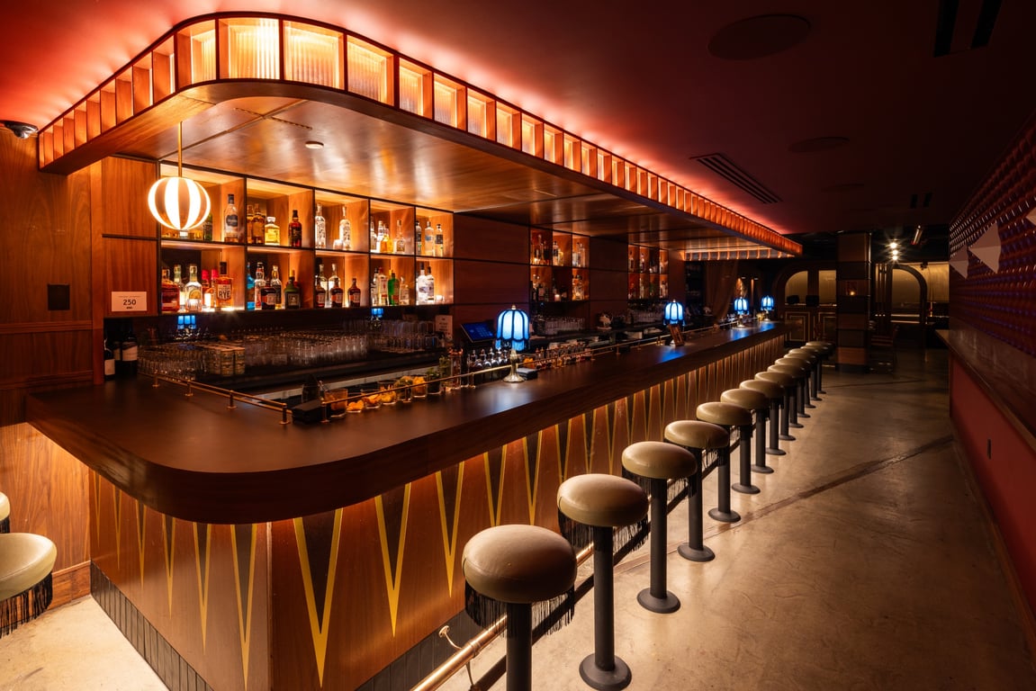 This New Restaurant & Lounge in Midtown Is Inspired By the Bygone “Mad Men” Era | Agency of Record vinyl wall | Agency of Record velvet curtain entrance | Agency of Record bar seating | Agency of Record signature cocktail | Agency of Record seating | Agency of Record fire and drinks | Agency of Record dinner spread | Agency of Record restaurant floor