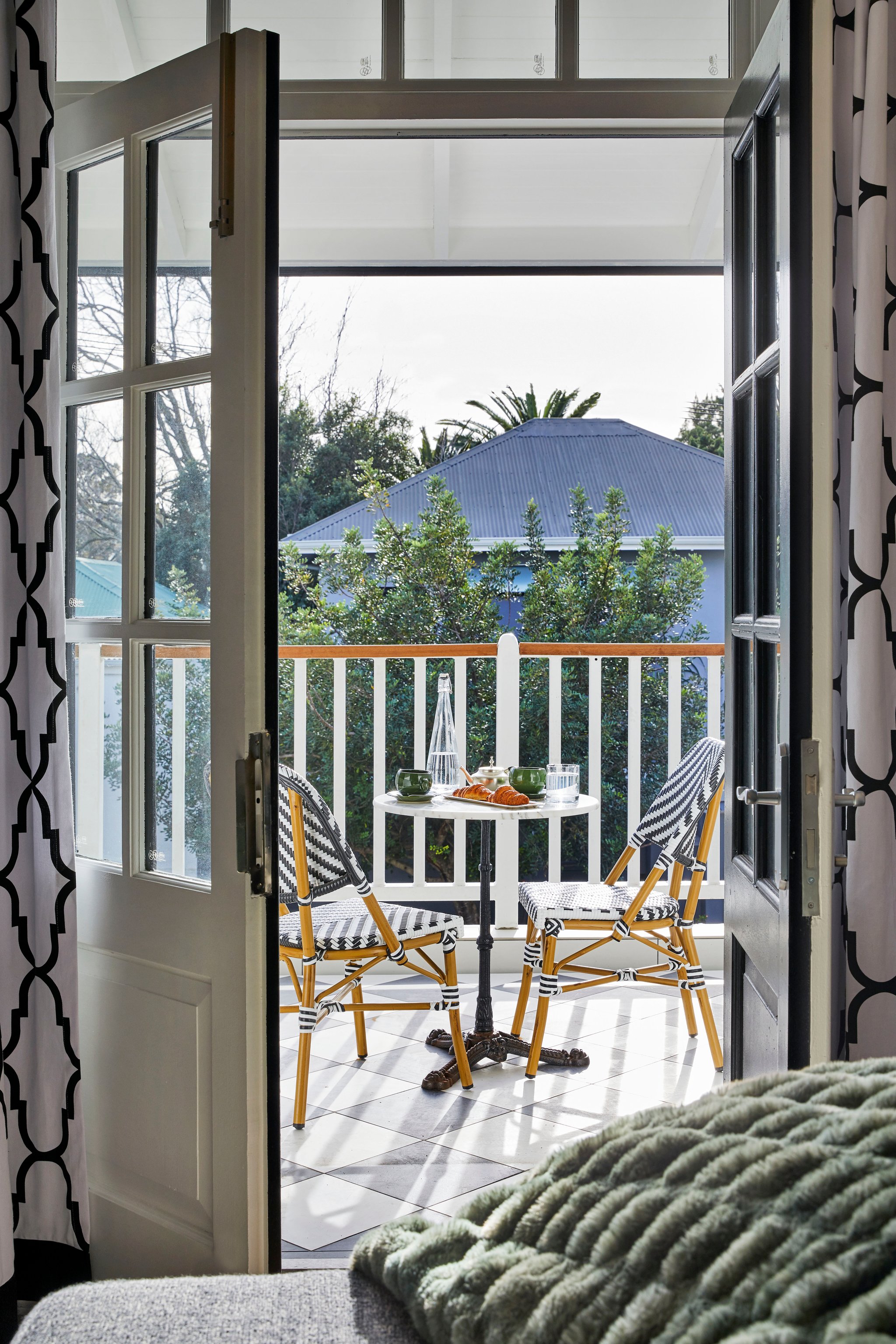 Private balcony with bistro seating and croissant breakfast overlooking Gardens neighbourhood.