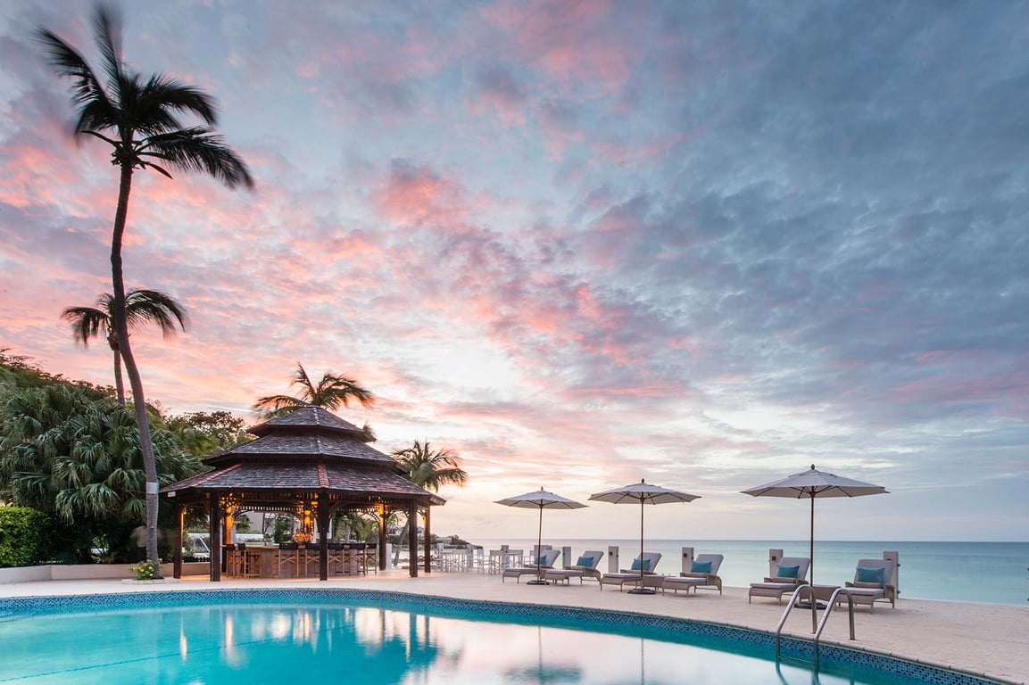 This Luxury Boutique Hotel in Antigua Embodies the Island Lifestyle | Blue Waters Resort & Spa aerial view | Blue Waters Resort & Spa restaurant and bar | Blue Waters Resort & Spa castle | Blue Waters Resort & Spa bedroom suite | Blue Waters Resort & Spa poolside seating | Blue Waters Resort & Spa spa | Blue Waters Resort & Spa restaurant seating | Blue Waters Resort & Spa evening view on the water