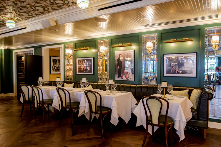 Saint Theo’s Is the New York City Restaurant Everyone is Talking About | Inside of the New York City restaurant, St. Theo's. There is a large bar with white bar stools. | St. Theo's restaurant appetizers and menu | St. Theo's restaurant fish dish | St. Theo's bar interior. The outside of the bar has a wooden design. | Inside of the New York City restaurant, St. Theo's. There is a large bar with white bar stools. | Saint Theo's plates | Saint Theo's seating | St. Theo's drink | Inside of the New York City restaurant, St. Theo's. There is a large bar with white bar stools.