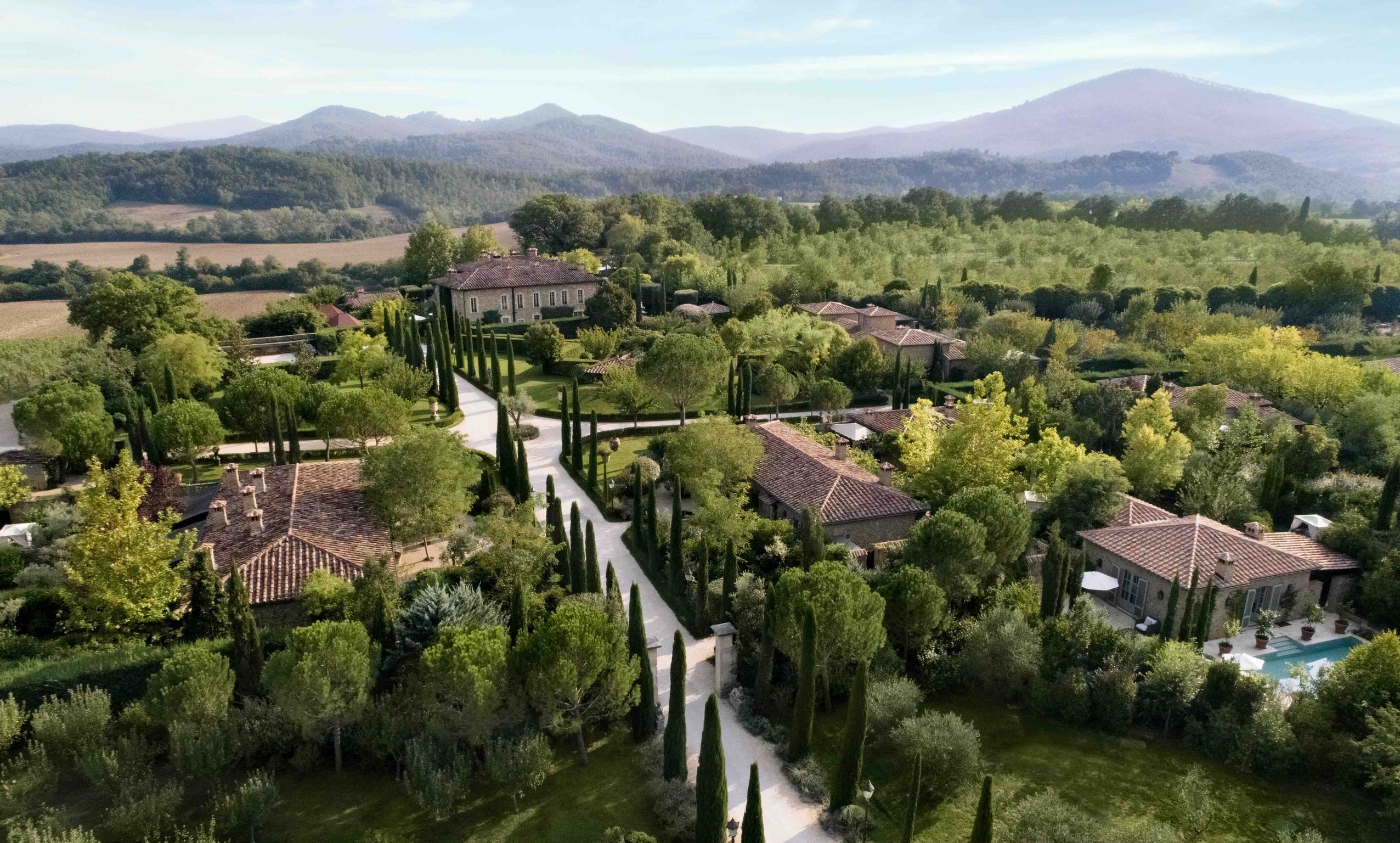 Borgo Santo Pietro hotel nestled among the rolling green hills of Tuscany, Italy, showcasing its beautiful countryside landscape.