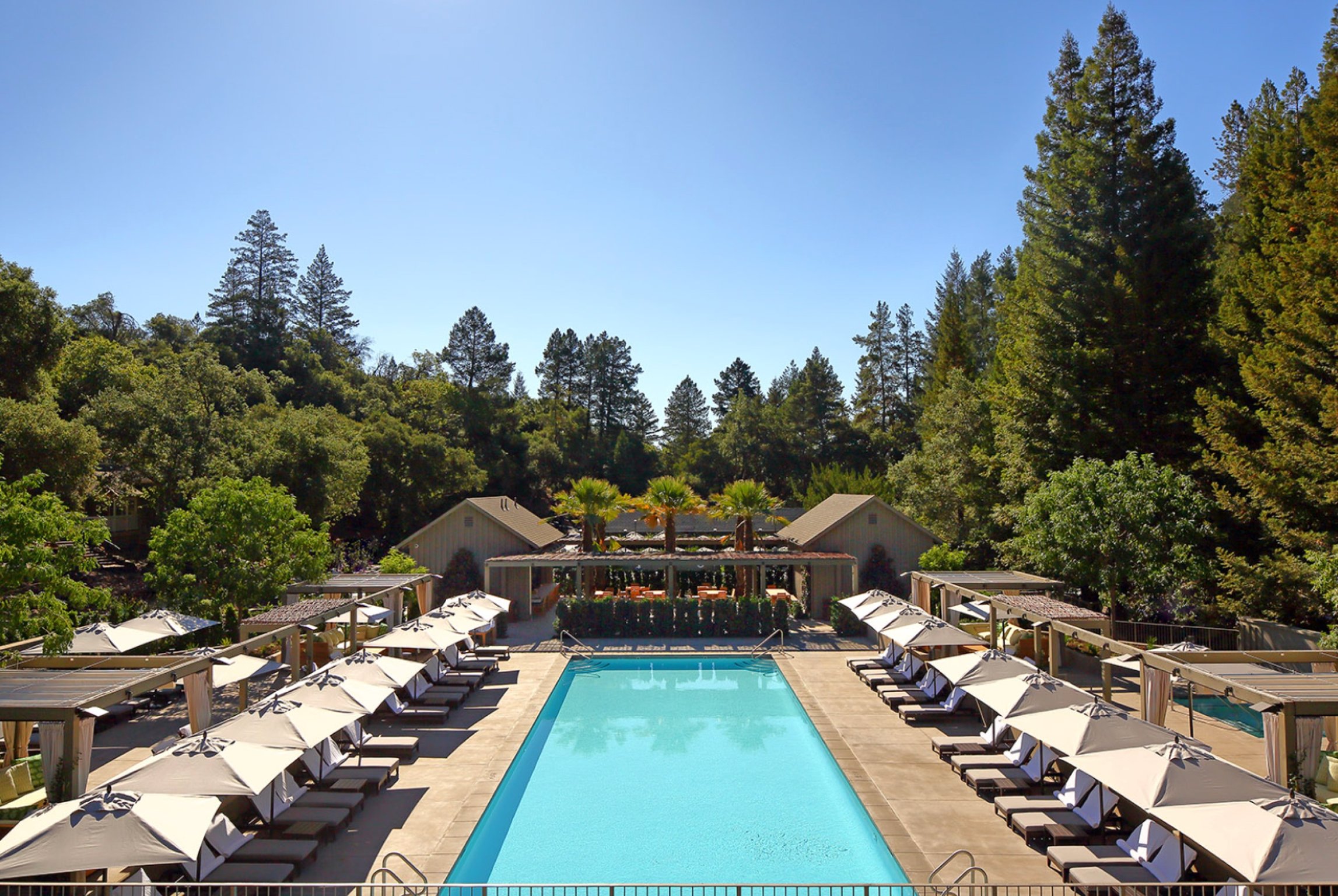 This 5-Star Napa Valley Retreat Will Make You Feel Like a Celebrity | Meadowood Napa Valley seating by fireplace | Meadowood Napa Valley tennis courts | Meadowood Napa Valley wine glasses | Meadowood Napa Valley restaurant | Meadowood Napa Valley bedroom suite