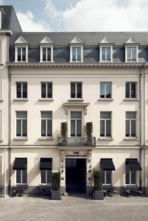 This City-center Hotel Brings Contemporary Style to the Site of an Ancient Abbey in Brussels | The Dominican Brussels exterior | The Dominican Brussels restaurant chairs in hallway | The Dominican Brussels restaurant | The Dominican Brussels suite bedroom | The Dominican Brussels suite | The Dominican Brussels restaurant
