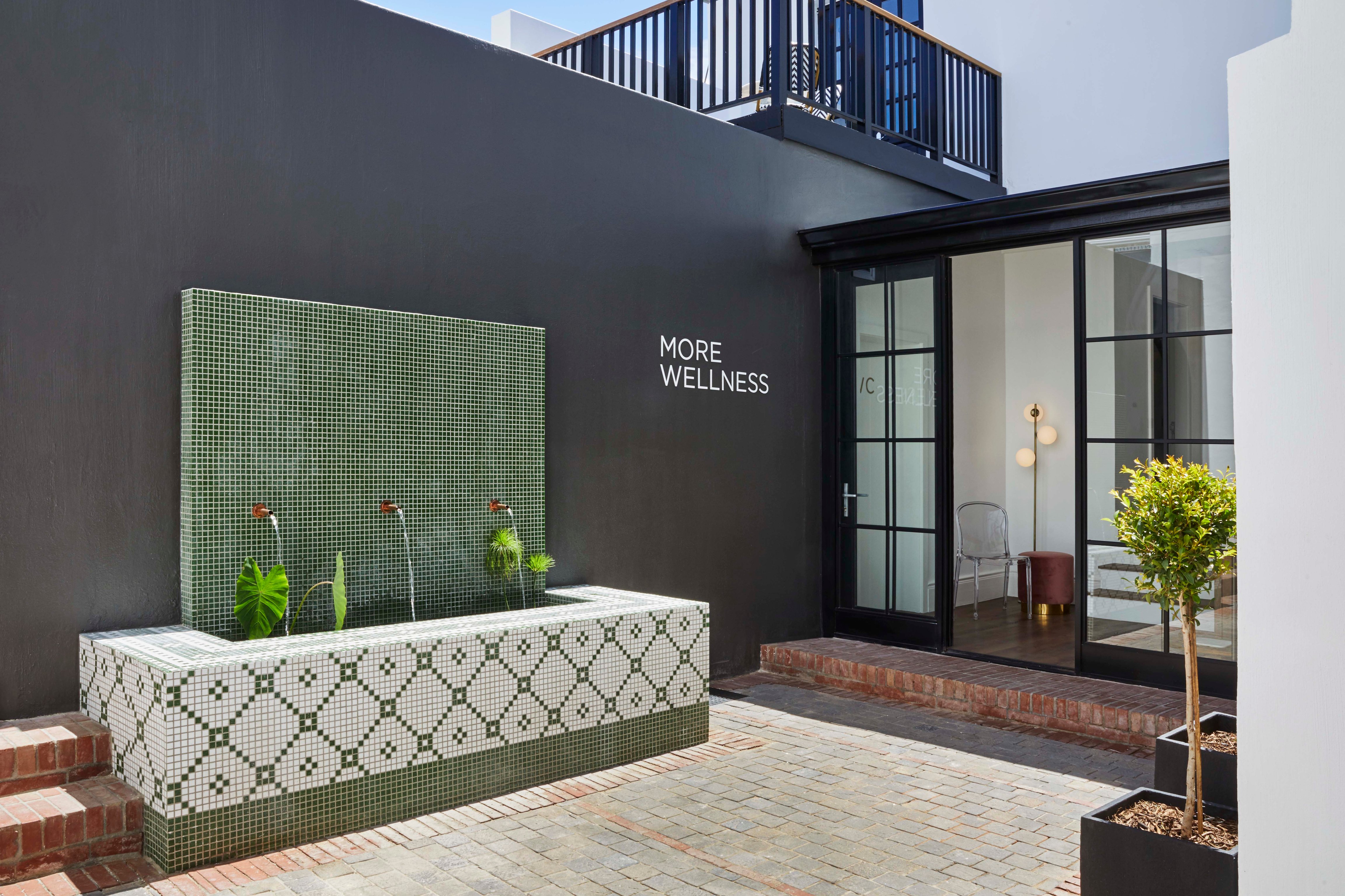More Wellness spa entrance with green mosaic water feature at Cape Cadogan.