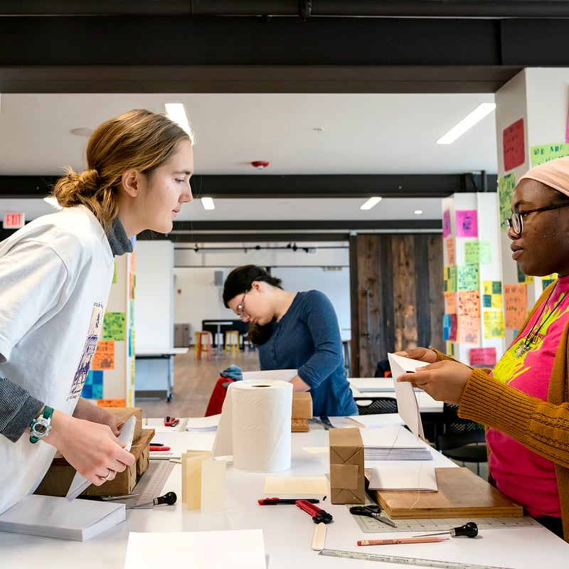 two students talking to each other with a student in the background