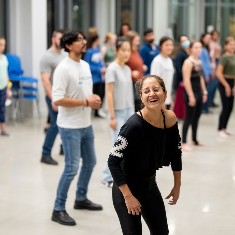 Sandra Bernal Heredia laughing while leading a dance class with participants in the background