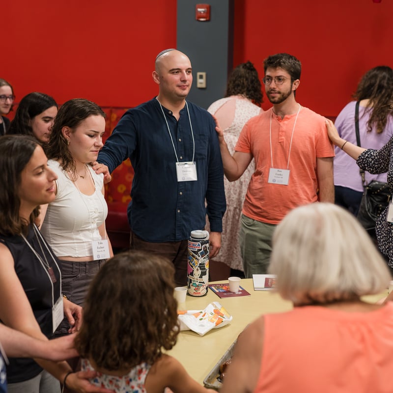 A group of people standing in a circle engaging and connecting during a gathering around a table