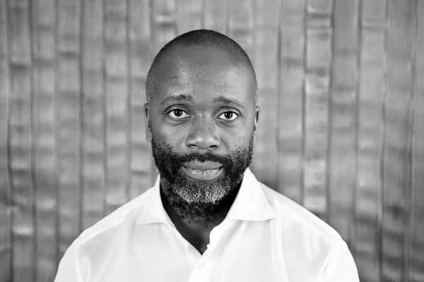 A portrait photograph of Theaster Gates captured in black and white.