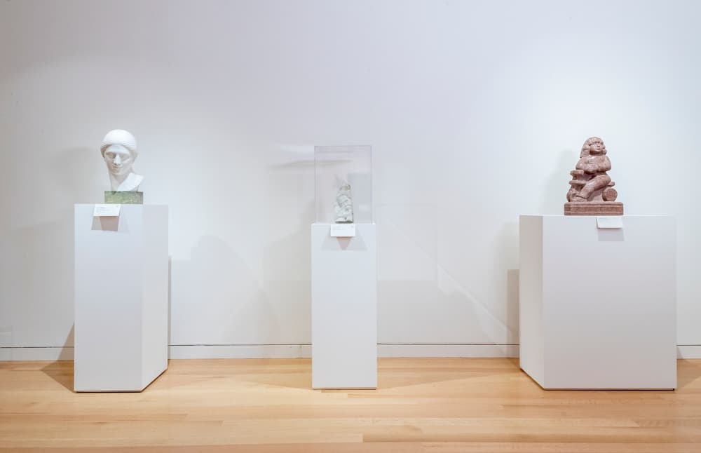 Three figurative sculptures installed on plinths in a white gallery.