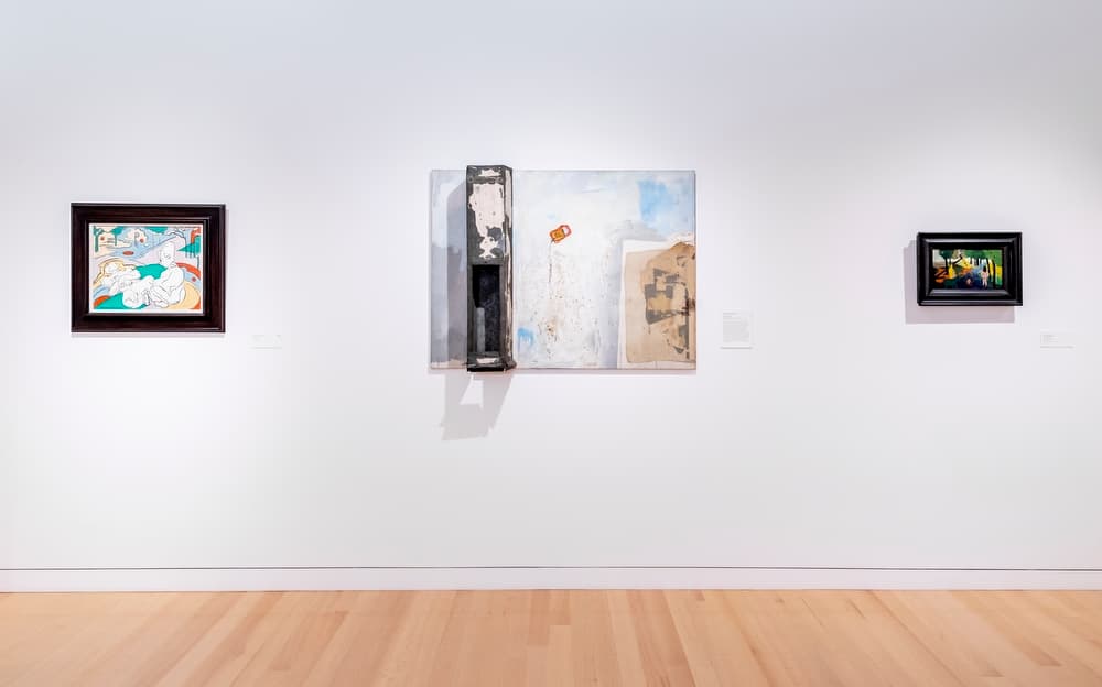 Three works of art hung side by side on a white wall.
