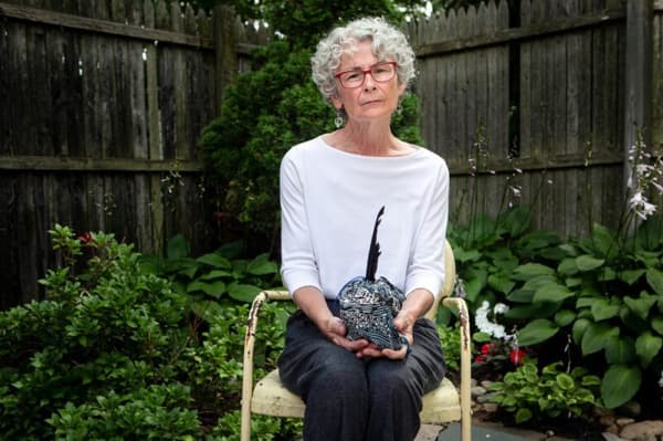 Karen Wentworth sits in her South Portland backyard on July 24, 2020, holding the concoction of life-ending drugs she kept in a tidy, feathered bundle.