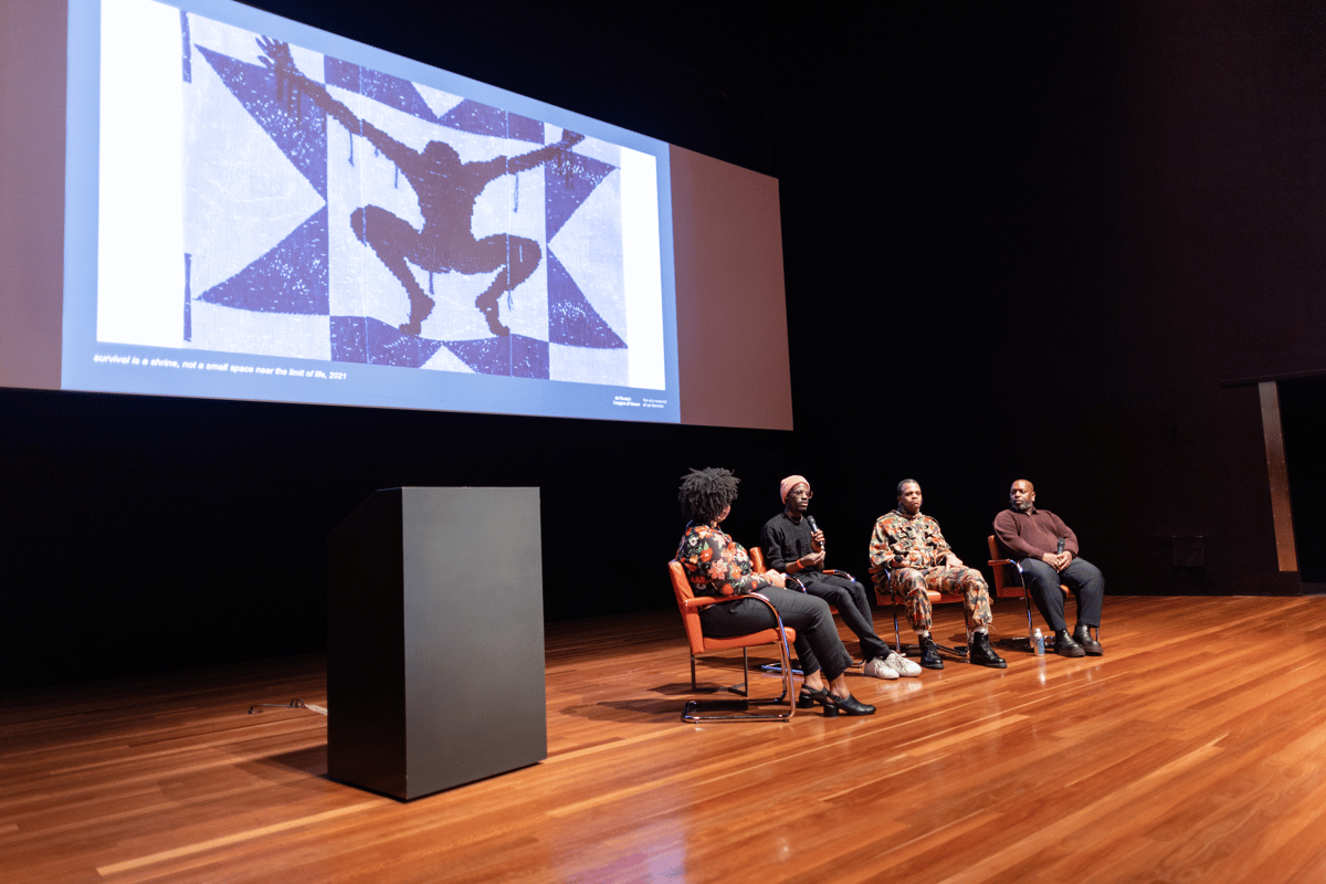 A group of panelists on stage at the de Young Museum.