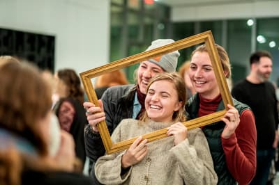 Three women posing with a frame