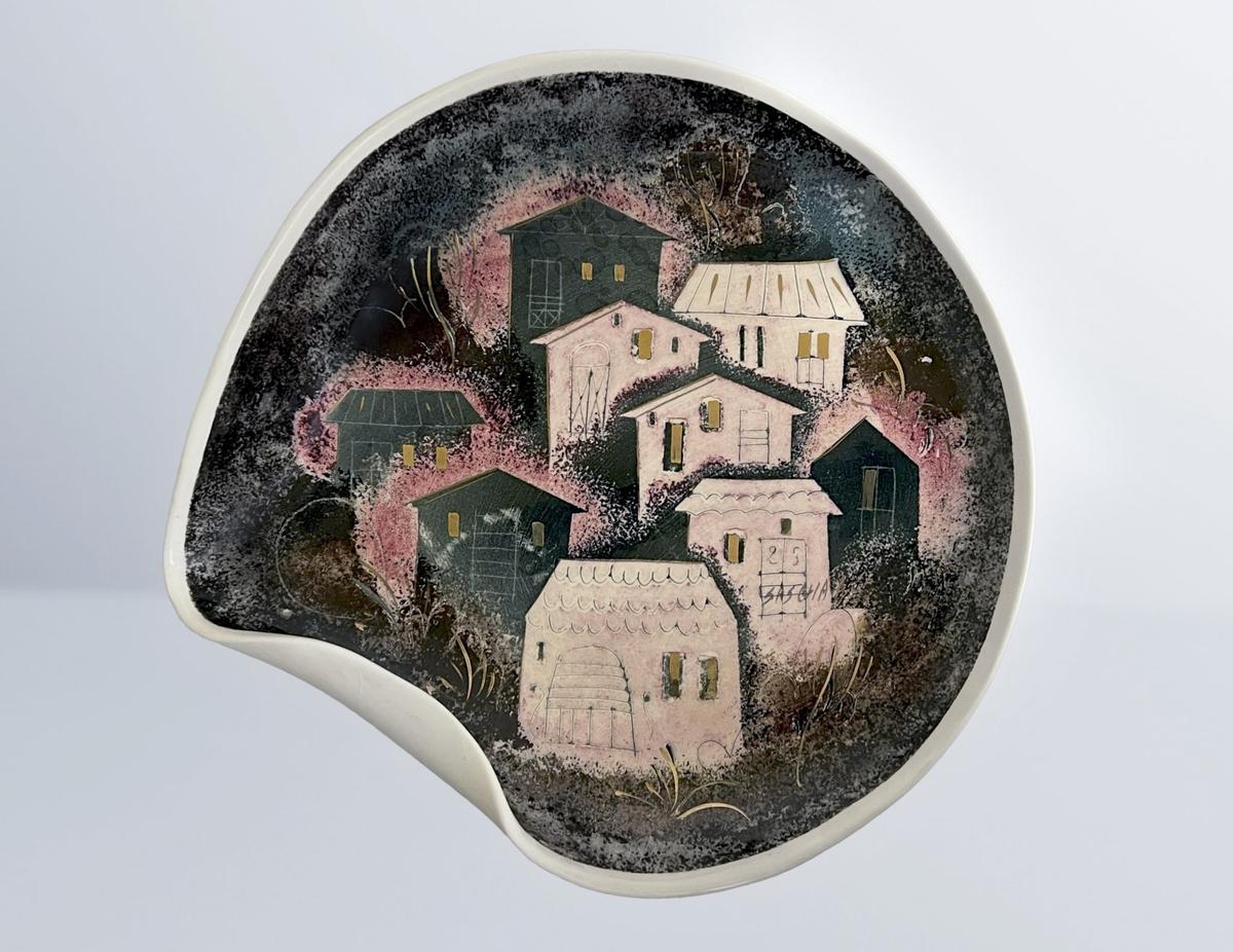 A ceramic object that depicts a folded plate with a cityscape adorned nine houses.