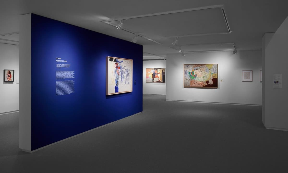 Art gallery interior with abstract and contemporary paintings on white and blue walls.
