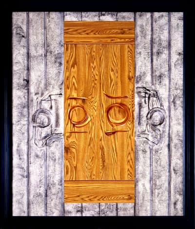 Artistic composition with a wooden panel and textured gray surfaces featuring copper elements and engraved designs.