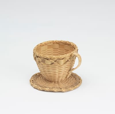Sculpture of a tea cup and saucer made from brown ash and sweetgrass.