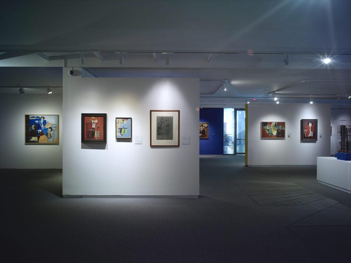 Art gallery interior with abstract and contemporary paintings on white and blue walls.