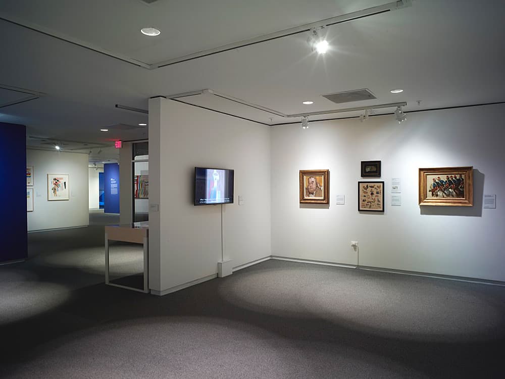 Art gallery interior with abstract and contemporary paintings as well as a tv monitor on white walls.