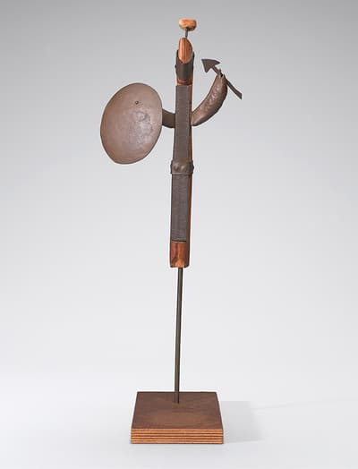 An abstract sculpture made from metal and wood on a square wooden base.