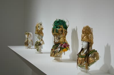 Four mannequin heads installed with large gold headresses.