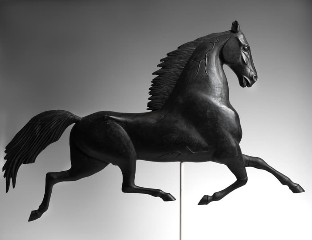 A weathervane in the shape of a black stallion.