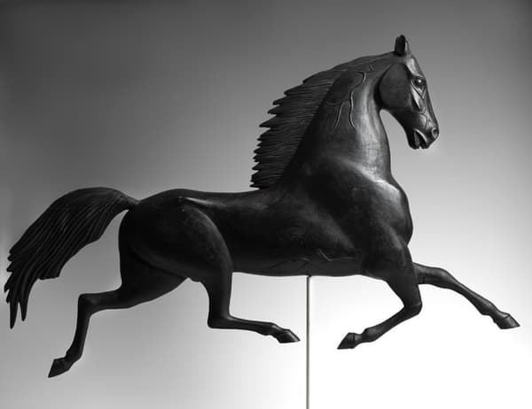 A weathervane in the shape of a black stallion.